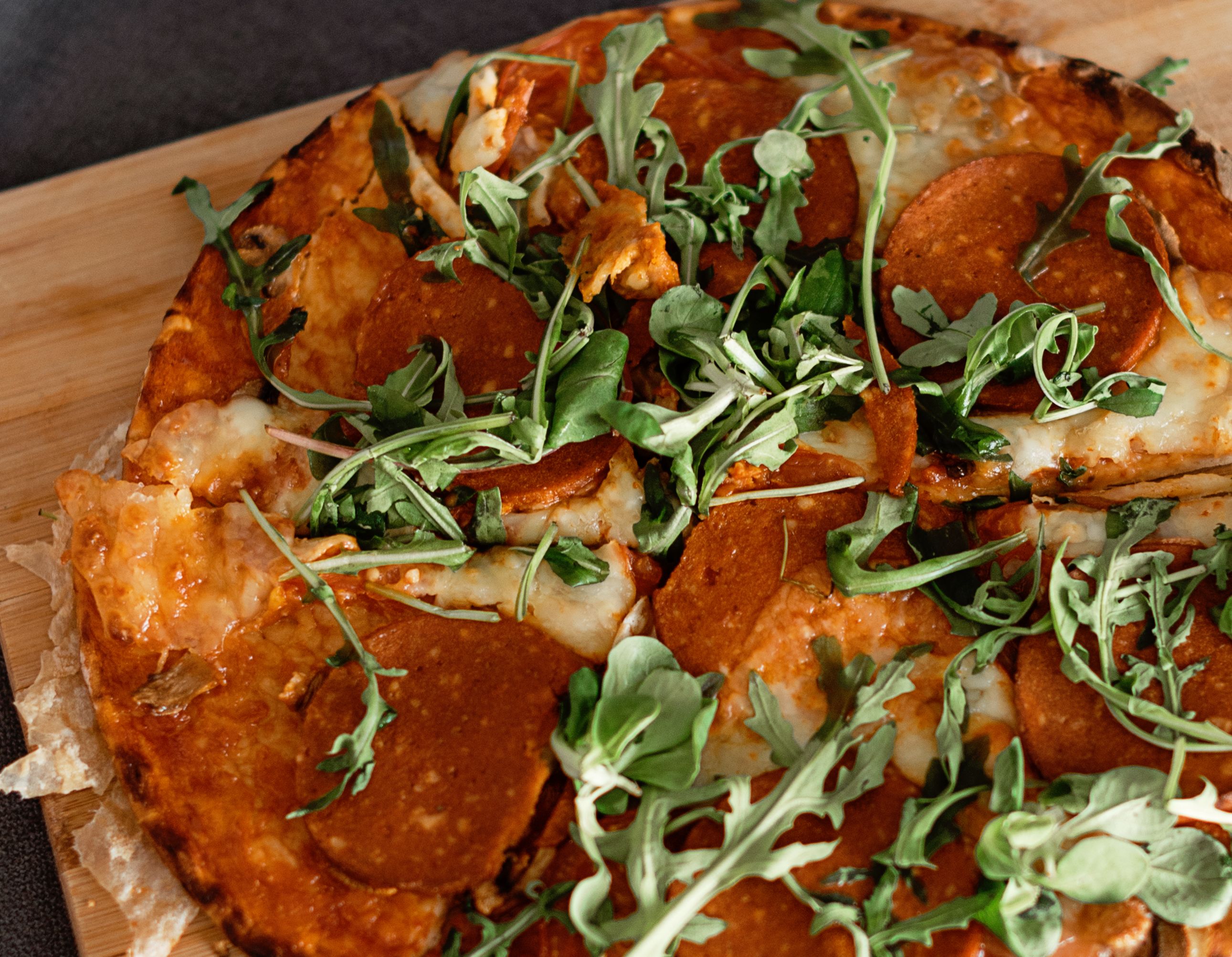 Domowa pizza z rukolą na drewnianej desce