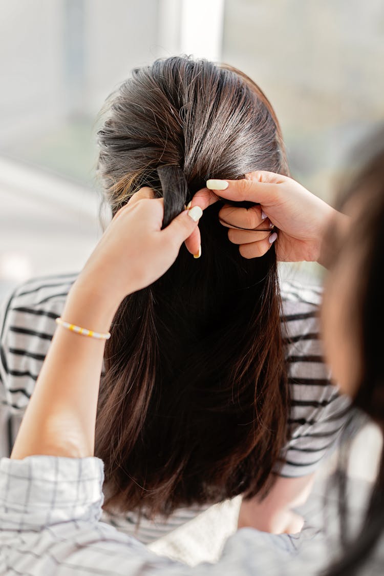 A Person Braiding A Woman's Hair