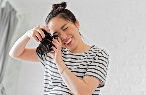 Woman in Her Striped Shirt Holding a Camera while Taking Photo