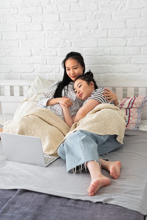 Free Two women cozy up together on a bed, showing affection and togetherness. Stock Photo