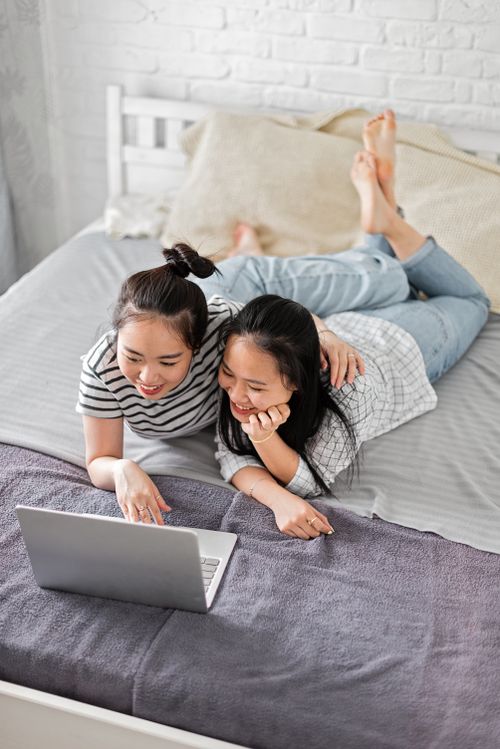 Free Happy couple enjoying time together on bed, browsing laptop in a cozy setting. Stock Photo