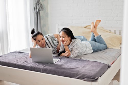 Free Women Lying on the Bed while Looking at the Laptop Stock Photo