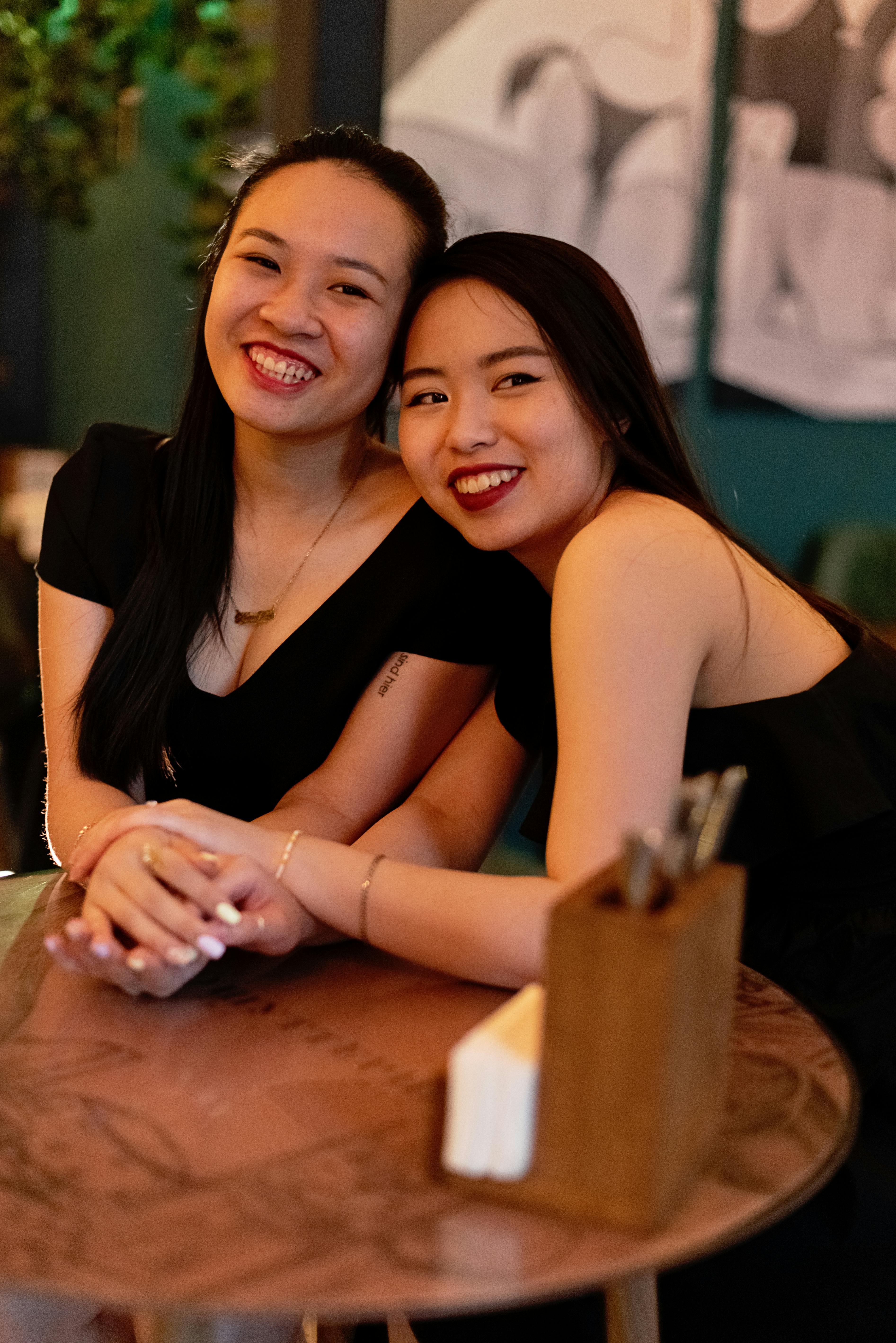 beautiful women in black top smiling while holding hands