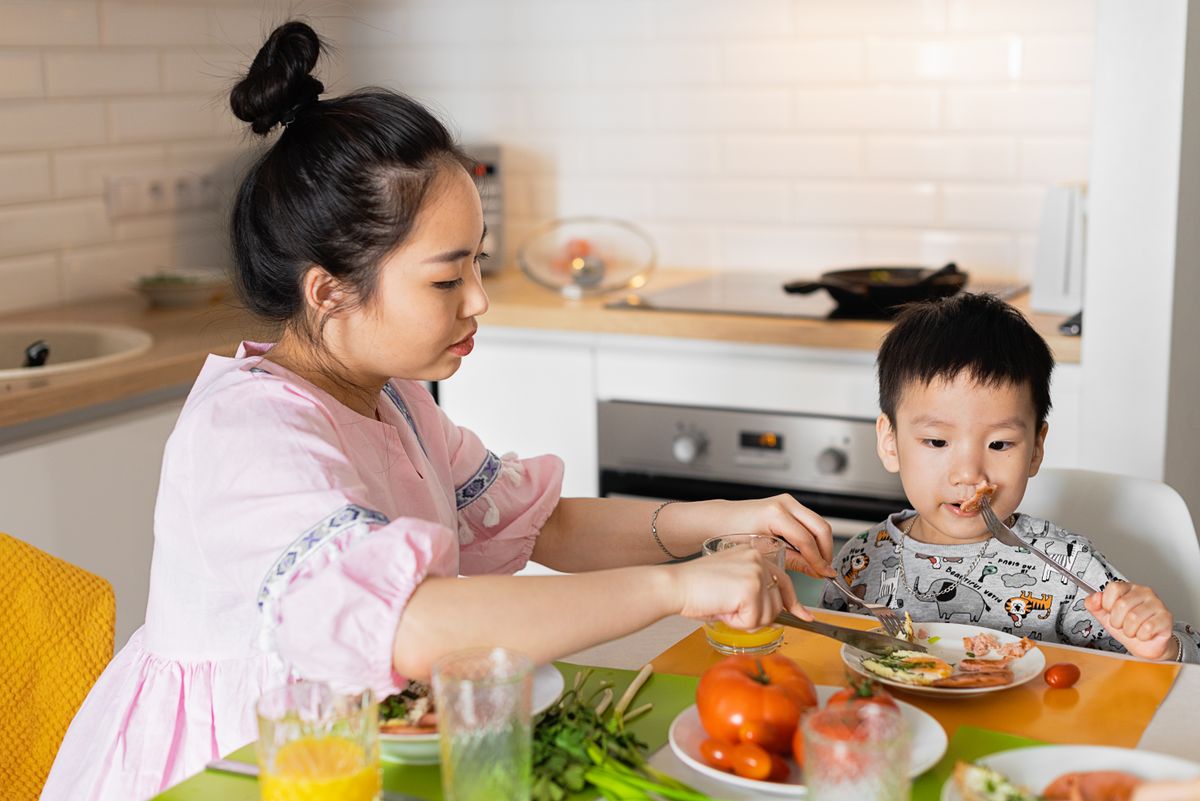 Une adulte prépare le repas d’un bébé installé à table