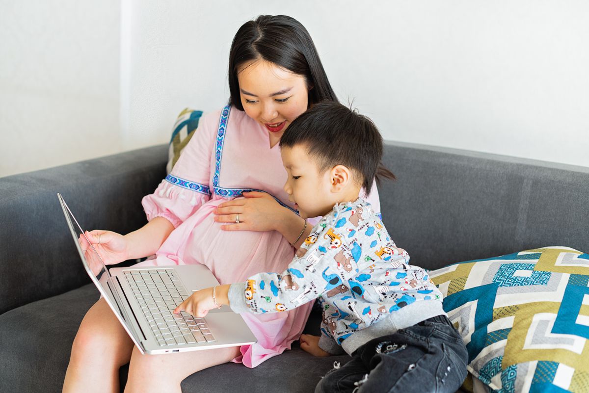 Pregnant mother and child using a laptop together at home