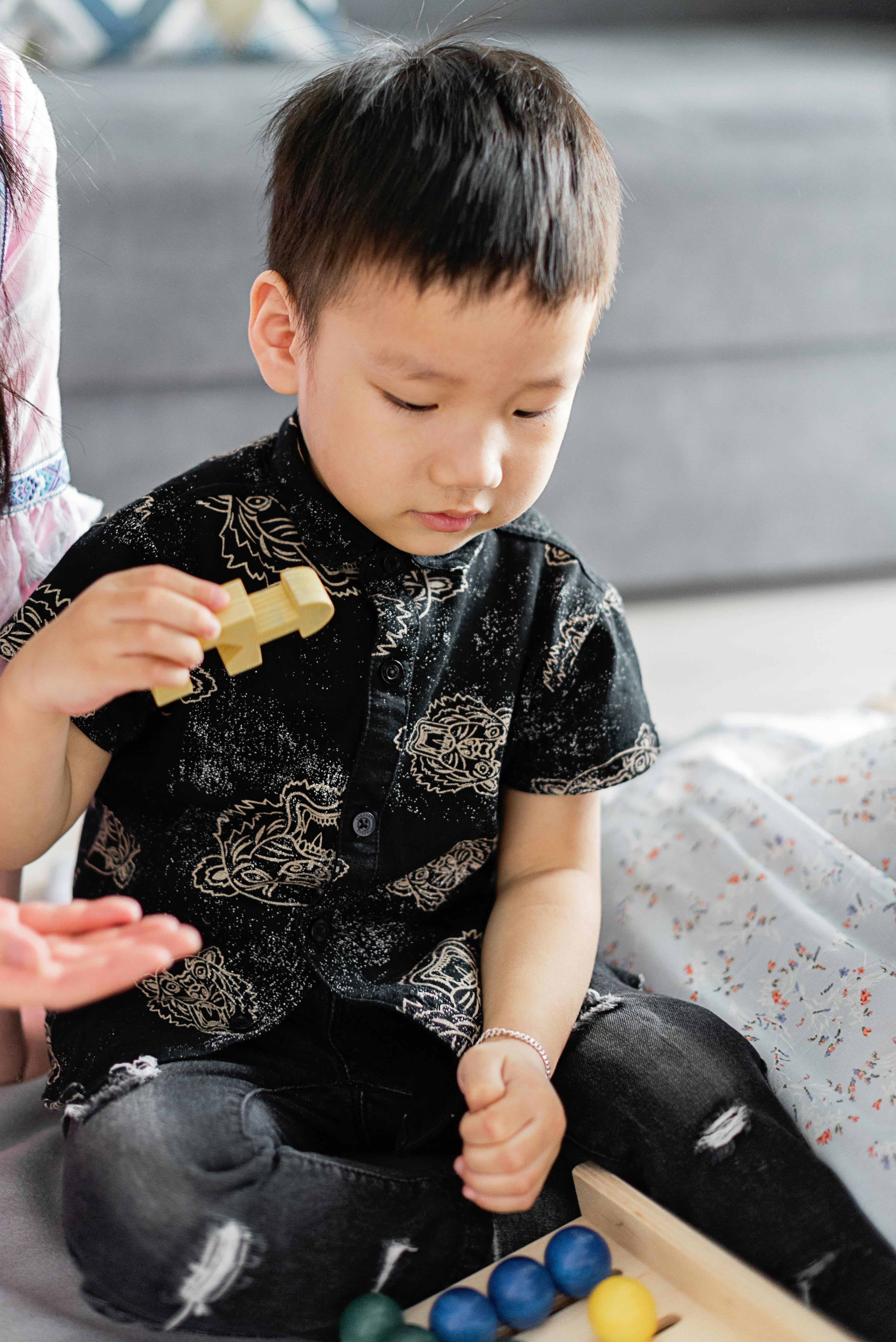 a boy in black clothing holding a piece of toy