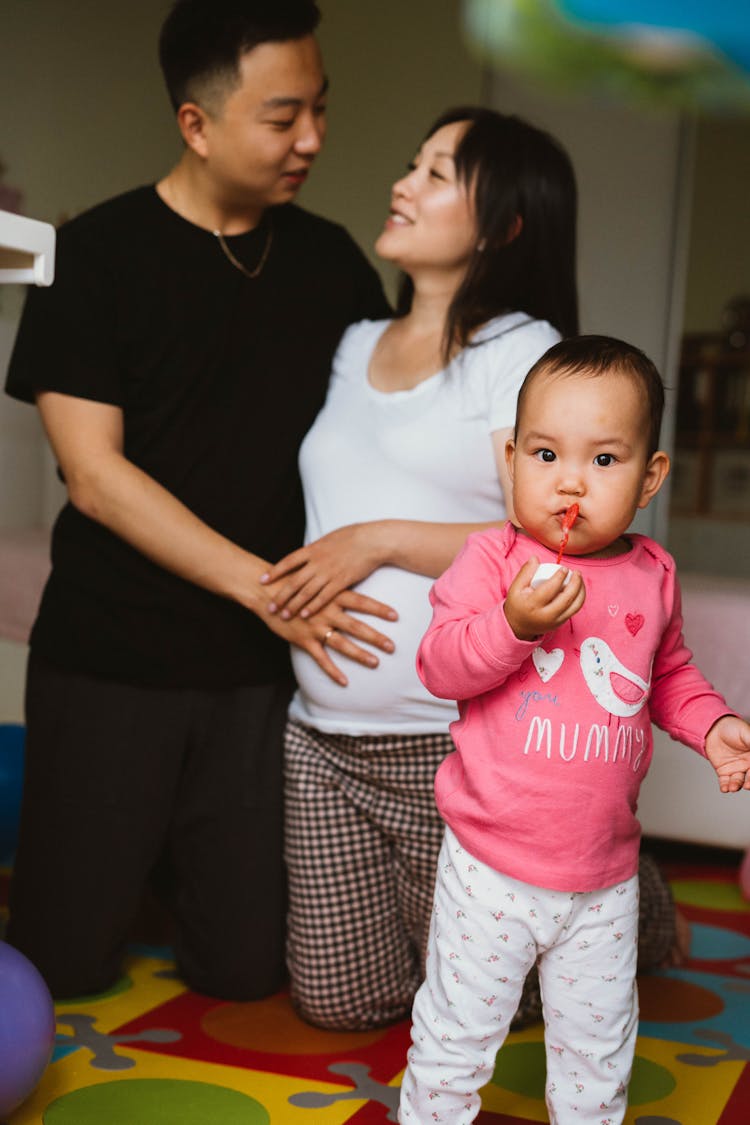 Happy Asian Family With Baby In Child Room