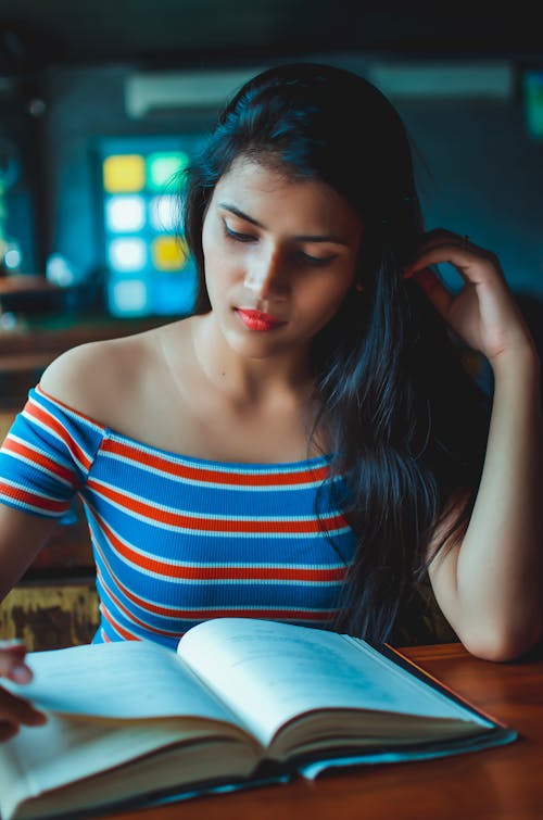 Beautiful Woman in a Striped Off Shoulder Top Reading a Book
