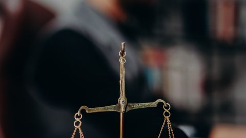 Close-up of justice scales and pipe on a lawyer's desk, emphasizing legal themes.