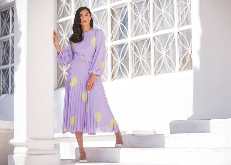 A Woman In Purple Dress Standing Near The Concrete Post