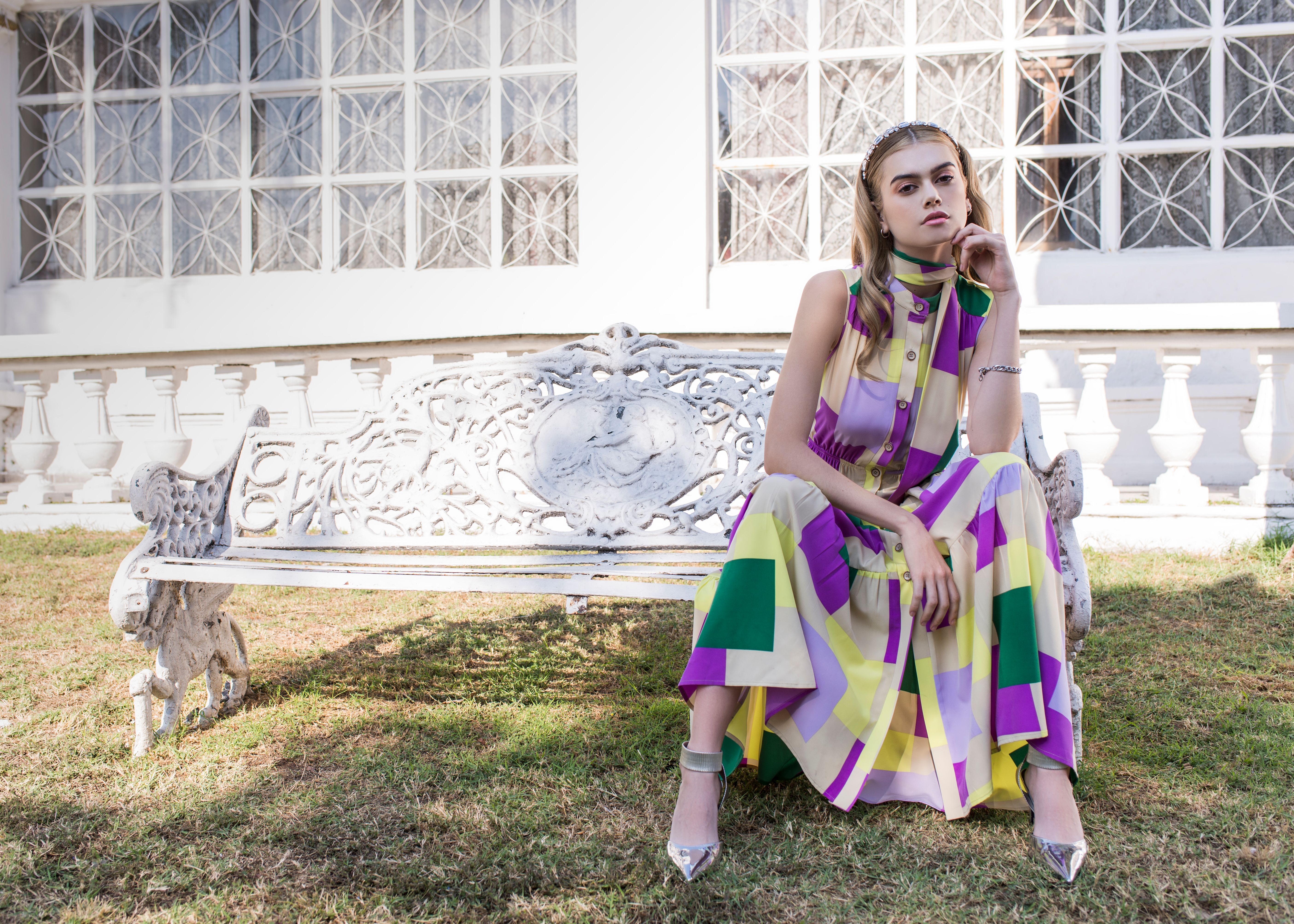 Model wearing a colorful statement dress styled with minimal accessories.