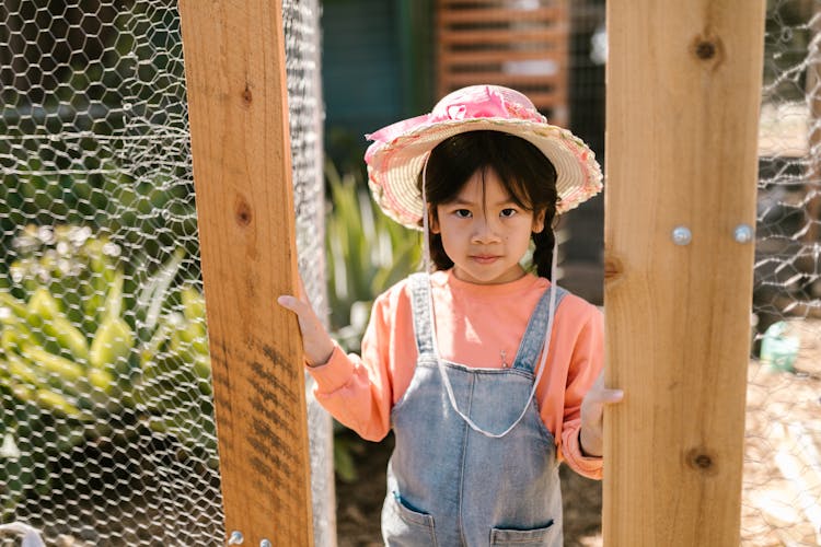 Girl In Jean Overalls Standing In Garden Entrance