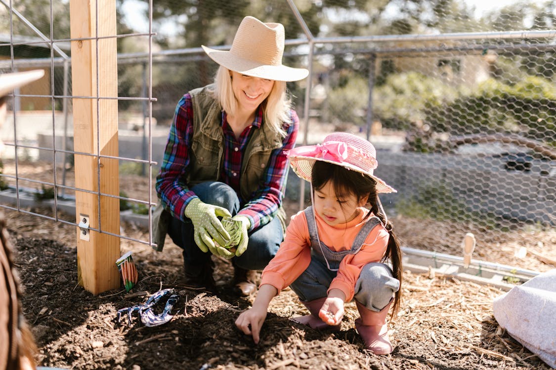 Free Woman and a Child Planting Seeds on the Ground Stock Photo