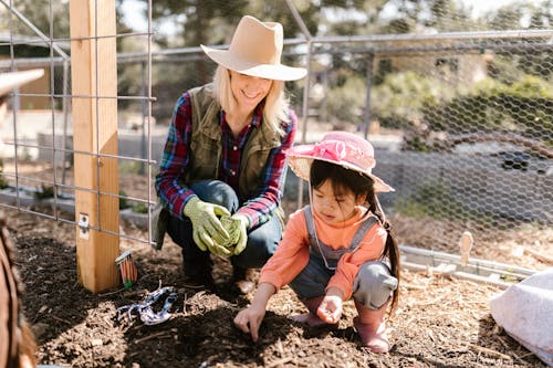 Woman and a Child Planting Seeds on the Ground