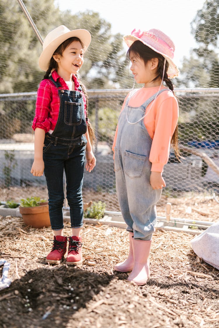 Girls In Jean Overalls Standing On Farm