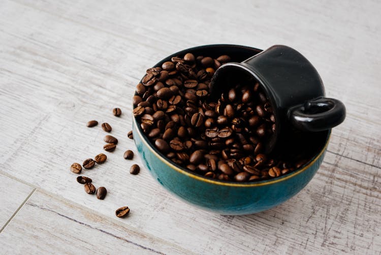 Black Mug Placed In Bowl With Aromatic Coffee Beans