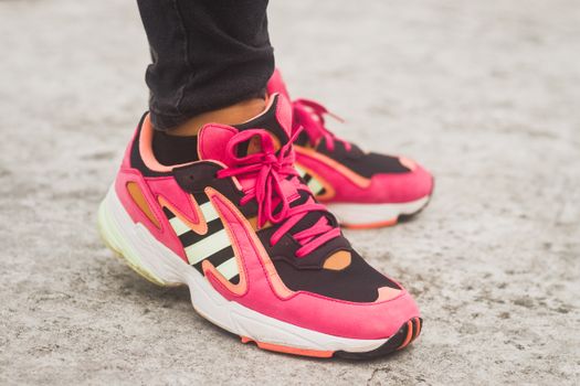 Close-up view of stylish pink sneakers with laces on a concrete floor