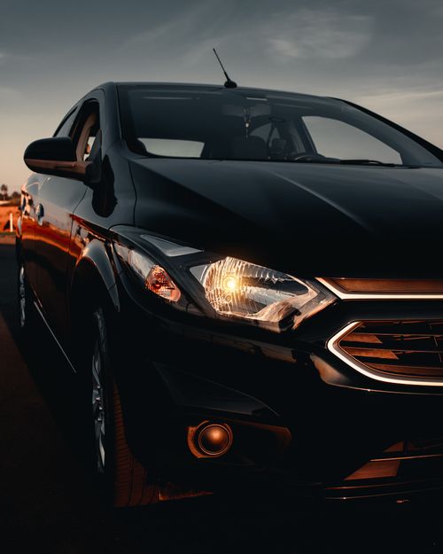 Free Stylish black car with illuminated headlight captured during sunset, showcasing automotive elegance. Stock Photo