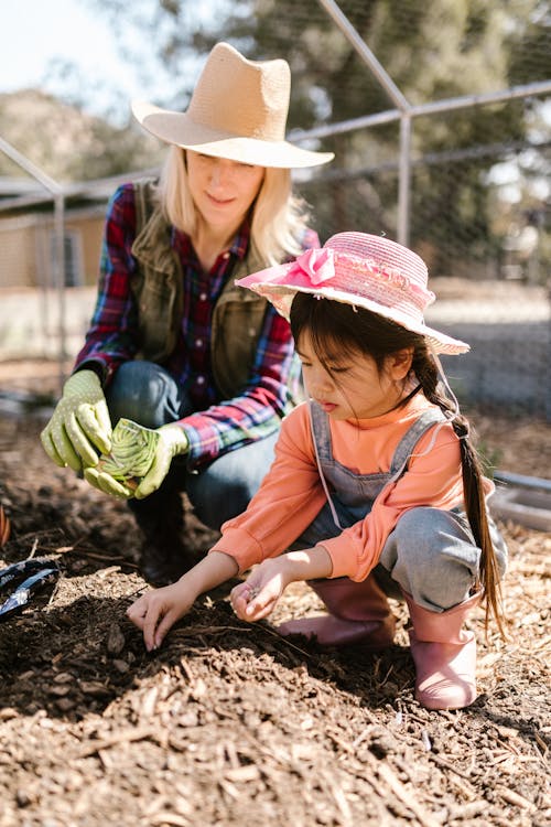 Woman and Young Girl Planting Seeds Together 