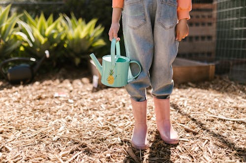 Free Close-up Photo of Child wearing Pink Boots and carrying Water Sprinkler  Stock Photo