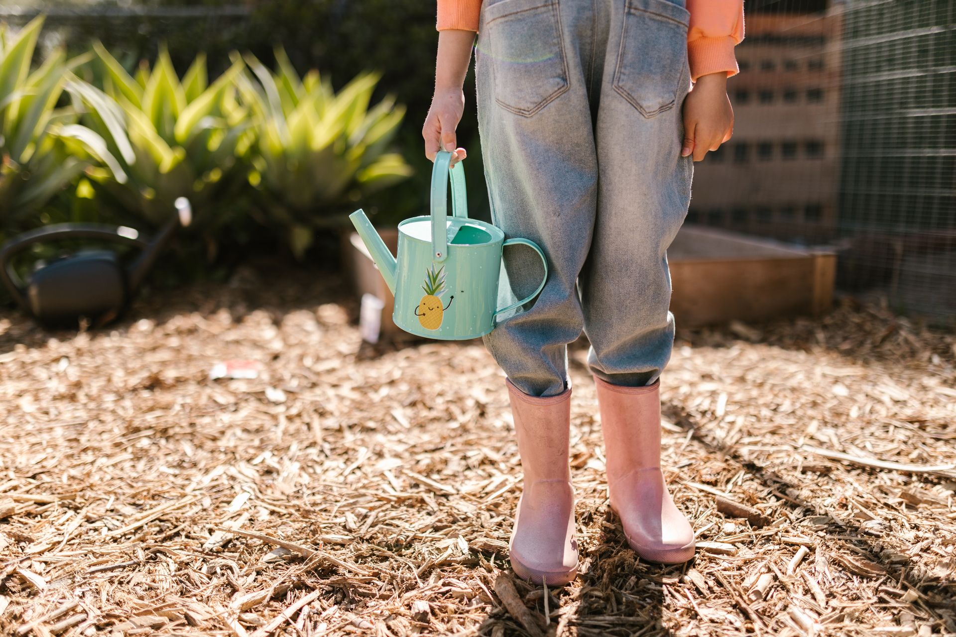 Close-up Photo of Child wearing Pink Boots and carrying Water Sprinkler