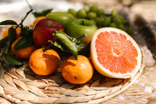Free Vibrant assortment of fresh fruit including citrus and apples placed in a natural setting. Stock Photo