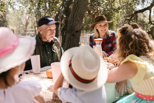 Free A joyful family picnic with adults and children enjoying a sunny day outdoors. Stock Photo