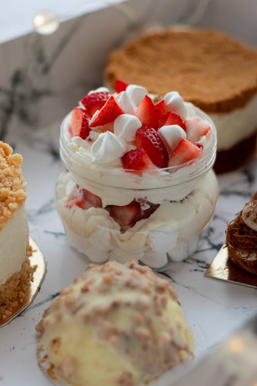 Free Jar of creamy parfait with strawberry placed in box among various yummy cakes including honey cake and cupcake with chocolate topping Stock Photo