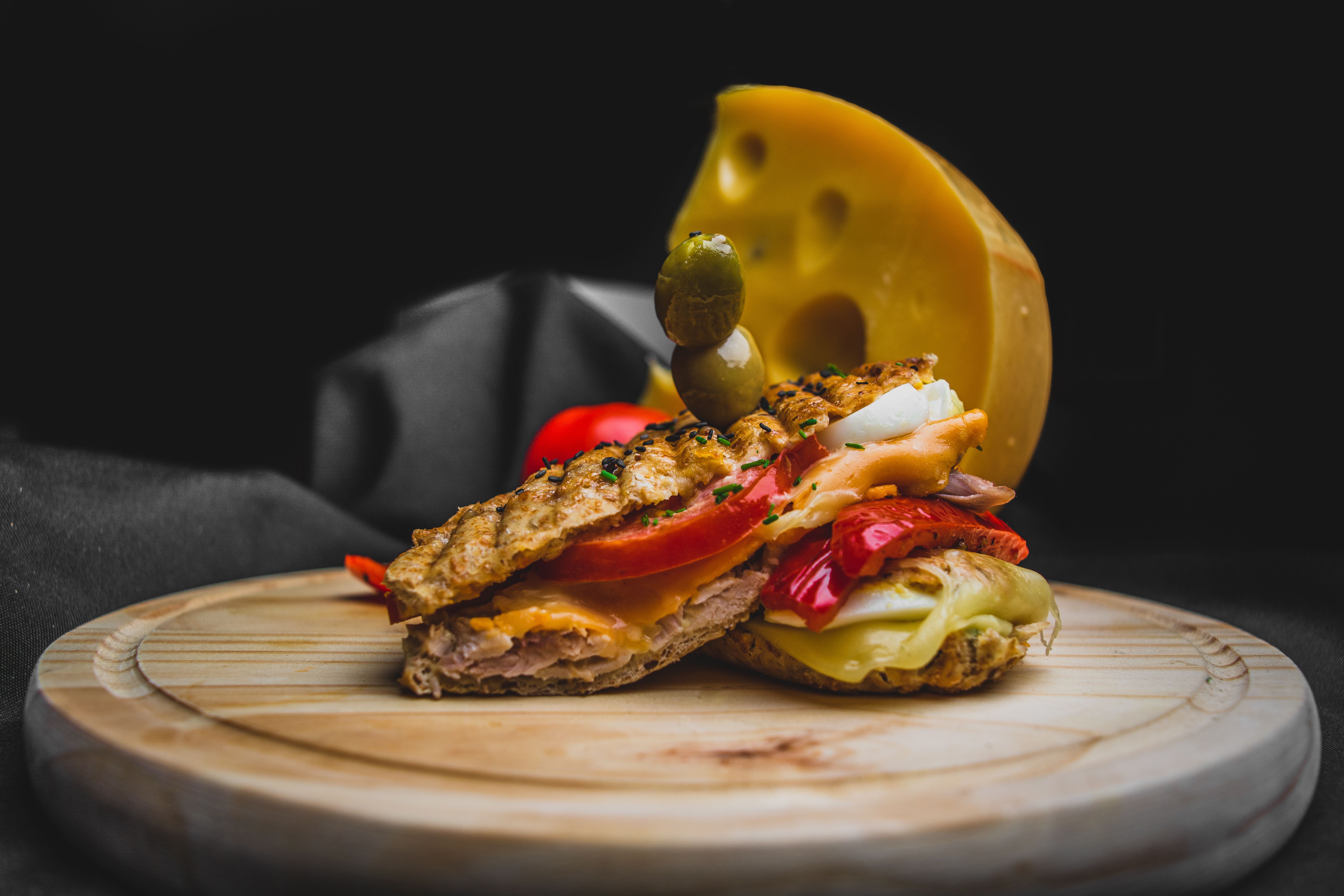 Savour this gourmet sandwich topped with cheese and olive, captured beautifully for food enthusiasts.