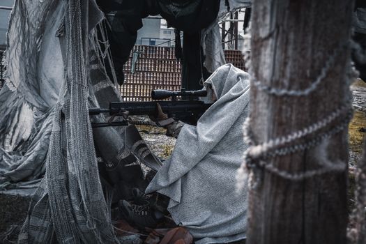 A soldier in camouflage aiming a sniper rifle outdoors, showcasing military stealth