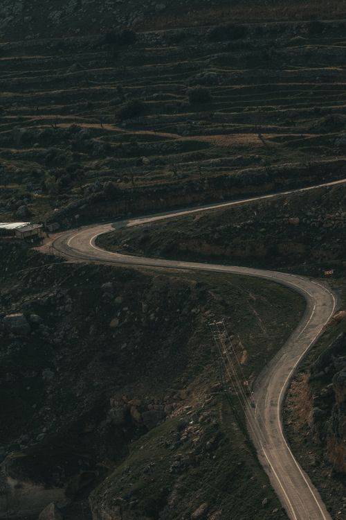 Free Aerial shot capturing a winding road through rural countryside with terraced fields. Stock Photo