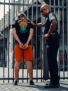 A Police Officer and a Man in Black Shirt Standing Near a Metal Fence