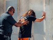 A Police Officer Frisking a Man in Black Shirt