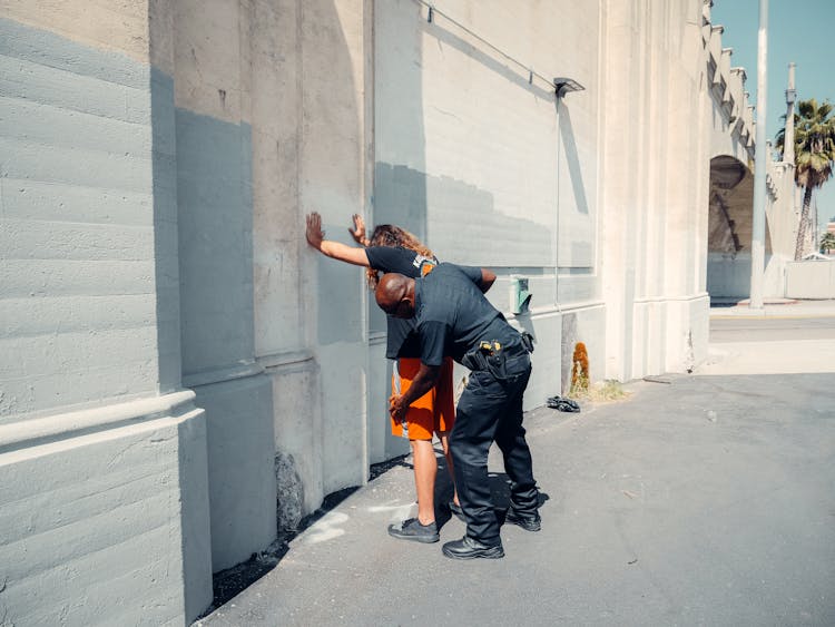 An Officer Frisking A Man