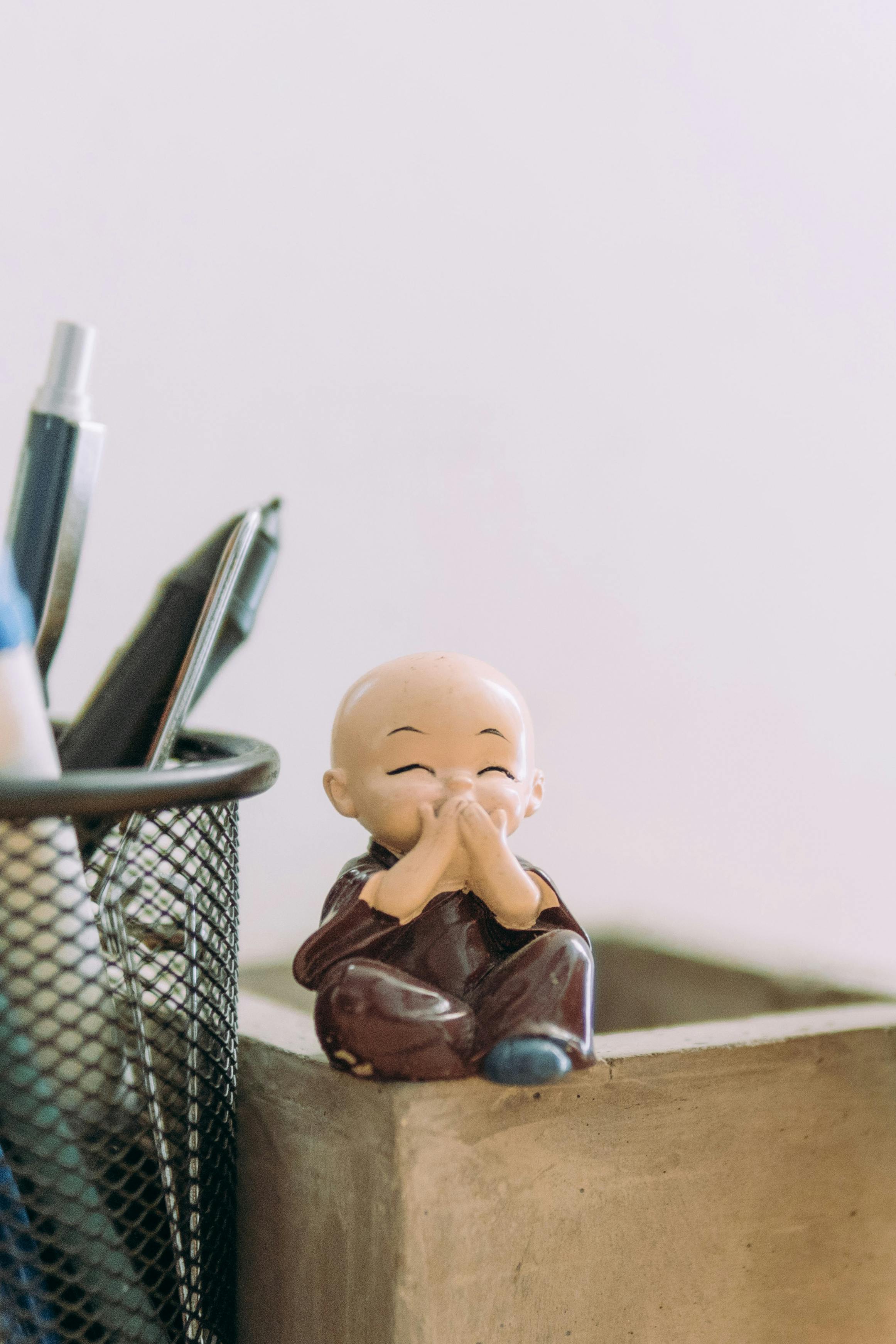 child figurine on a wooden box next to a pen holder