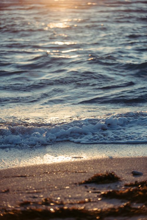 Free Peaceful beach scene with waves crashing ashore at sunset, creating a serene atmosphere. Stock Photo