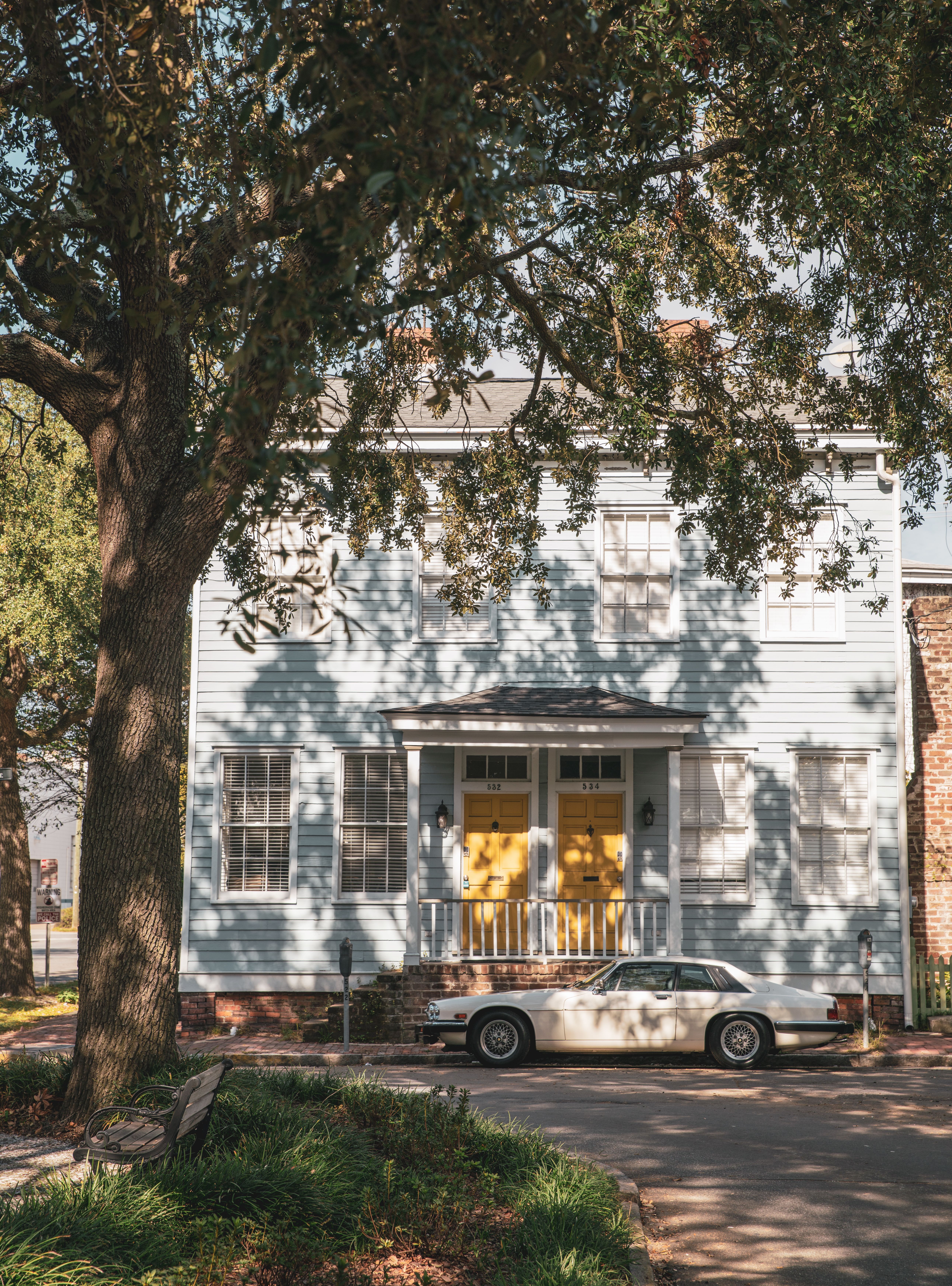 A White Car Parked in Front of a Wooden House · Free Stock Photo