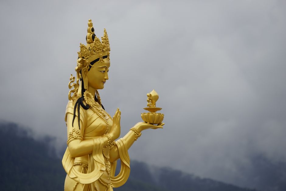 Majestic golden statue of a Buddhist deity in Thimphu, Bhutan against a cloudy sky.