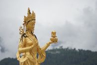 Majestic golden Buddhist statue in Thimphu showcasing spiritual artistry amidst nature.