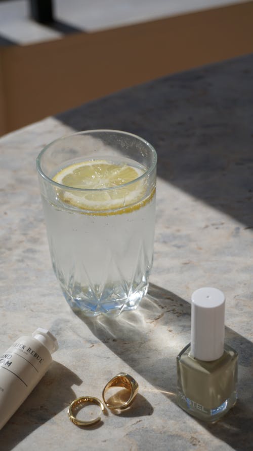Free Gold Rings Near a Glass of Water With Sliced Lemon Stock Photo