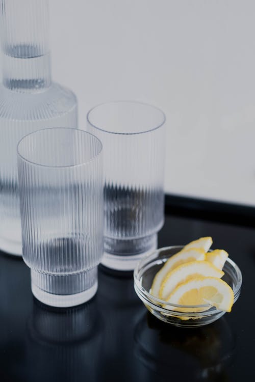 Free Lemon Slices, Drinking Glasses and a Pitcher of Water Stock Photo