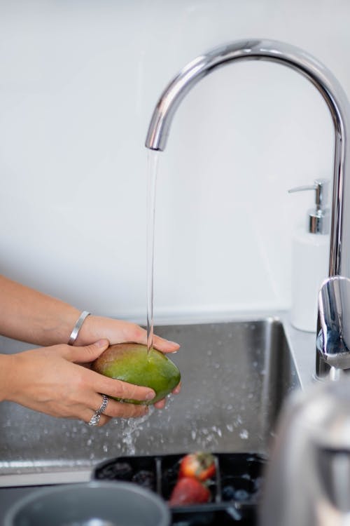 Person Washing a Green Fruit 