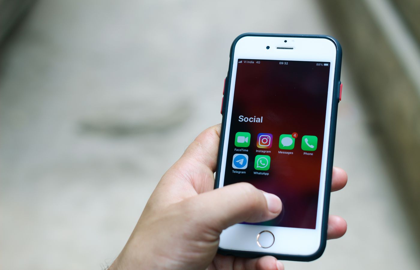 Hand holding a smartphone displaying various social media and communication apps.