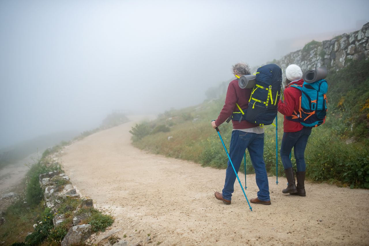 couple hiking in foggy portuguese countryside with backpacks enjoying
