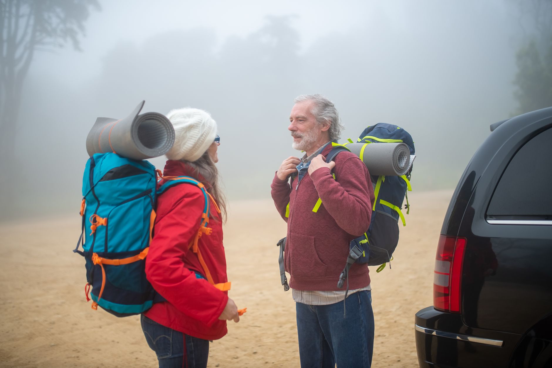 Un couple de personnes âgées actives en randonnée outdoor, conversant naturellement grâce à leur solution auditive.