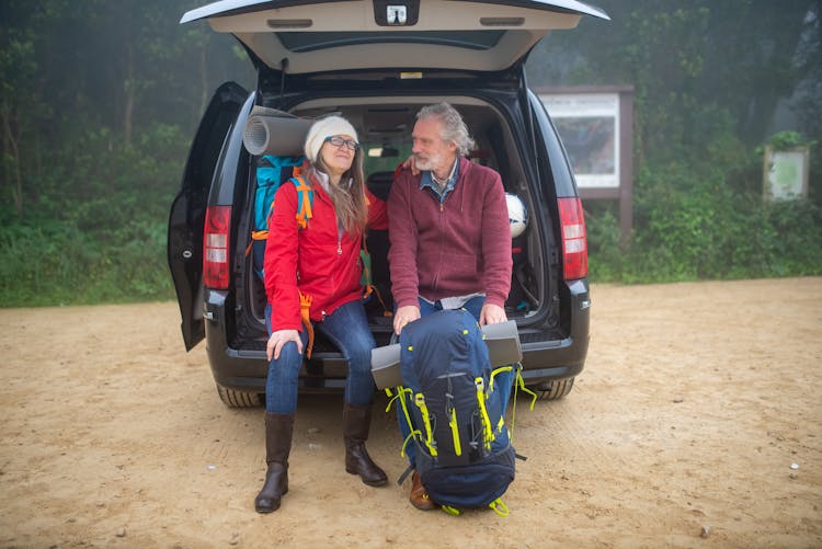 A Couple Sitting At The Back Of Black Van