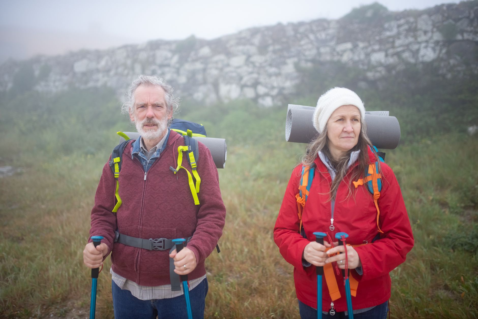 Older adults hiking with trekking poles, reflecting the physical-activity habits that remain visible in late-life longevity research.