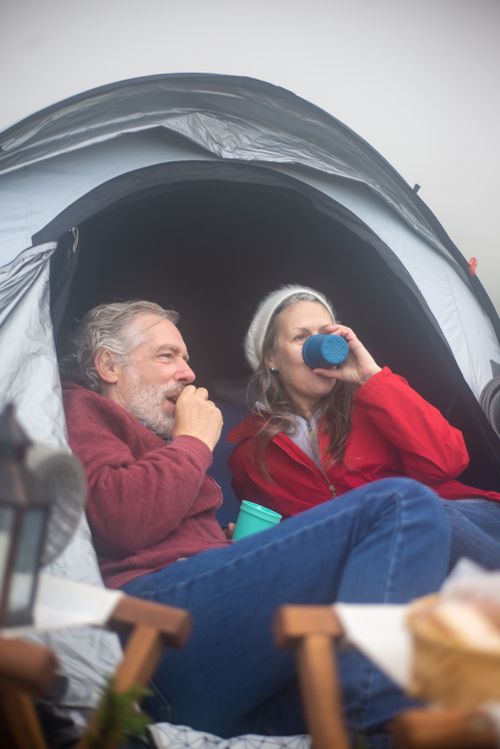 Free Relaxing camping scene with couple enjoying drinks outside their tent in Portugal. Stock Photo