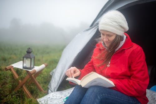 Free A Woman Reading a Book beside a Tent Stock Photo