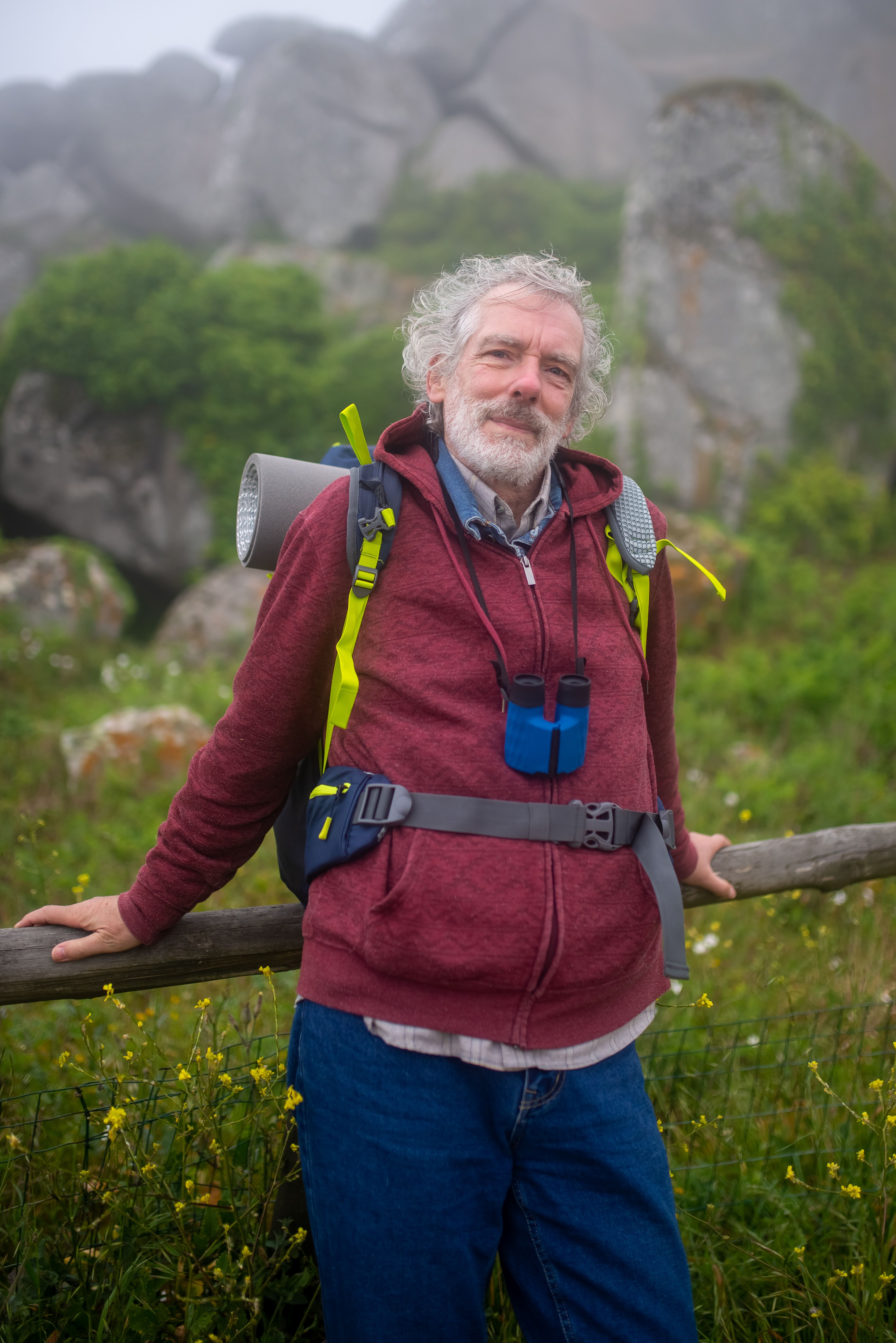 Elderly bearded man hiking in scenic Portugal landscape, showcasing adventure and nature's beauty.